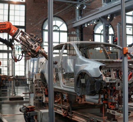 gray vehicle being fixed inside factory using robot machines